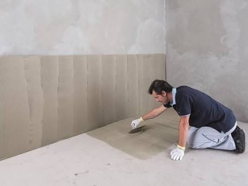 Installer setting large-format tile on a wall in a commercial buildout, Miami