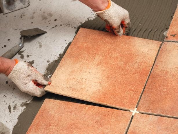 Installer setting terracotta floor tile with spacers over fresh thinset, Miami